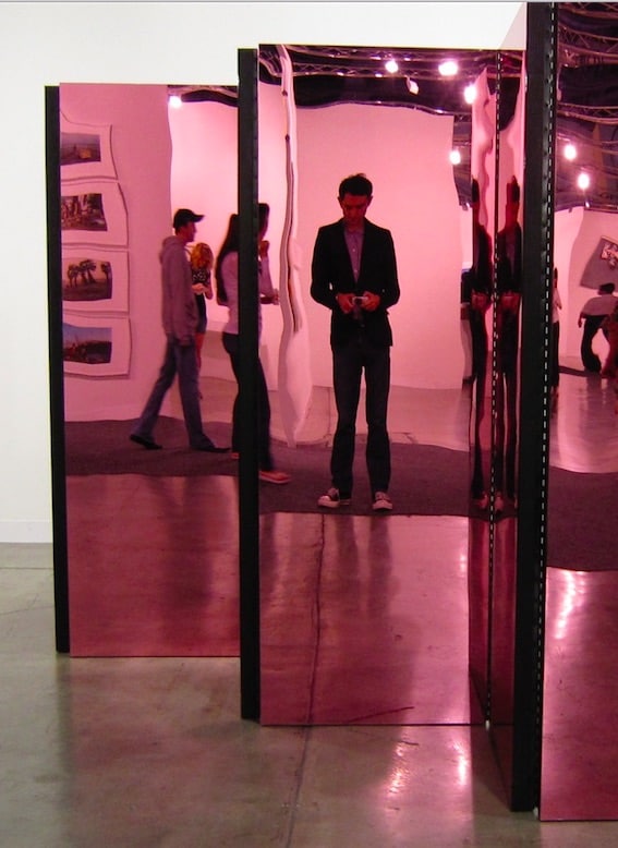 Check art, checking messages at a gallery during Art Basel in Miami in Towleroad and ManAboutWorld gay travel magazine