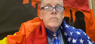 Gay School Board Member Claps Back at Anti-LGBT Witnesses by Donning Pride Flag During Meeting
